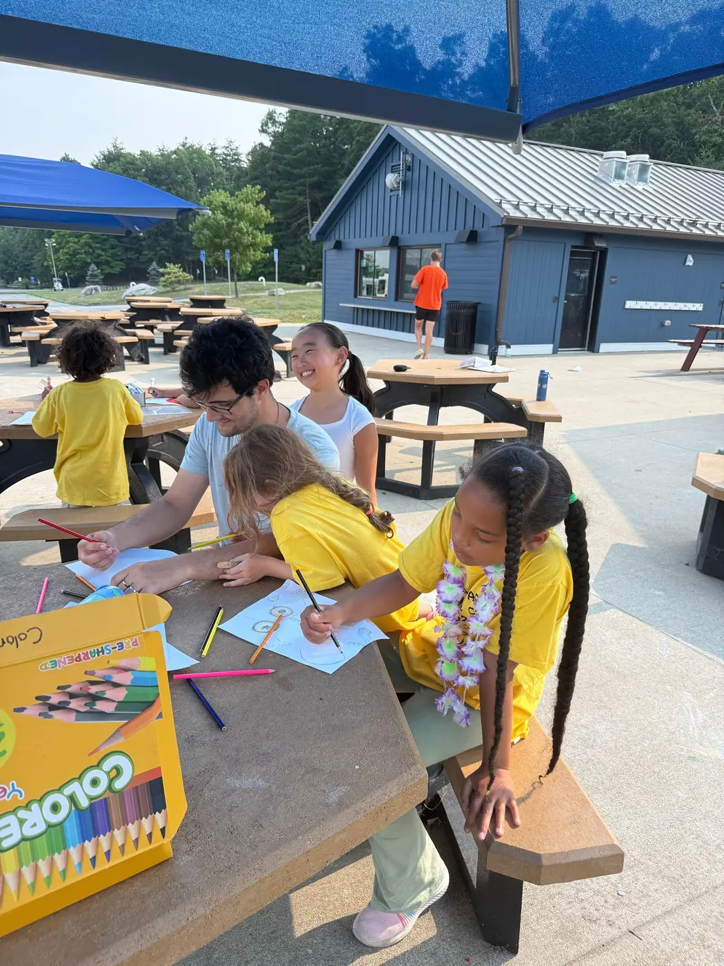 An instructor helping campers draw outdoors