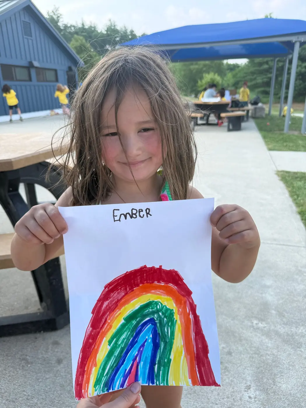 A camper sharing a finished rainbow drawing